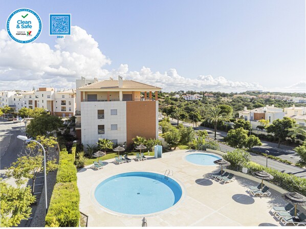 Relax by the two pools surrounded by lounge chairs and lush greenery.