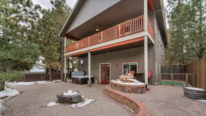A two-story house with a covered patio area featuring a hot tub, outdoor seating, and a fire pit. - Serenity in the Mountain Pines at The Cypress Point Lodge (Flagstaff)