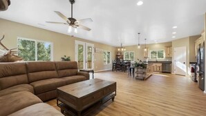 A spacious living room with a sectional sofa, a wooden coffee table, and a ceiling fan. - Serenity in the Mountain Pines at The Cypress Point Lodge (Flagstaff)