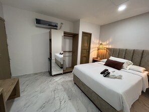 A hotel room with a large bed, a wooden headboard, a bedside table, a nightstand, a mirror, and an air conditioning unit. - HOTEL LA CASA 3 (Montería)