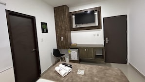 A compact hotel room with a kitchenette, a flat-screen TV mounted above the counter, and a pair of towels on the bed. - HOTEL LA CASA 3 (Montería)