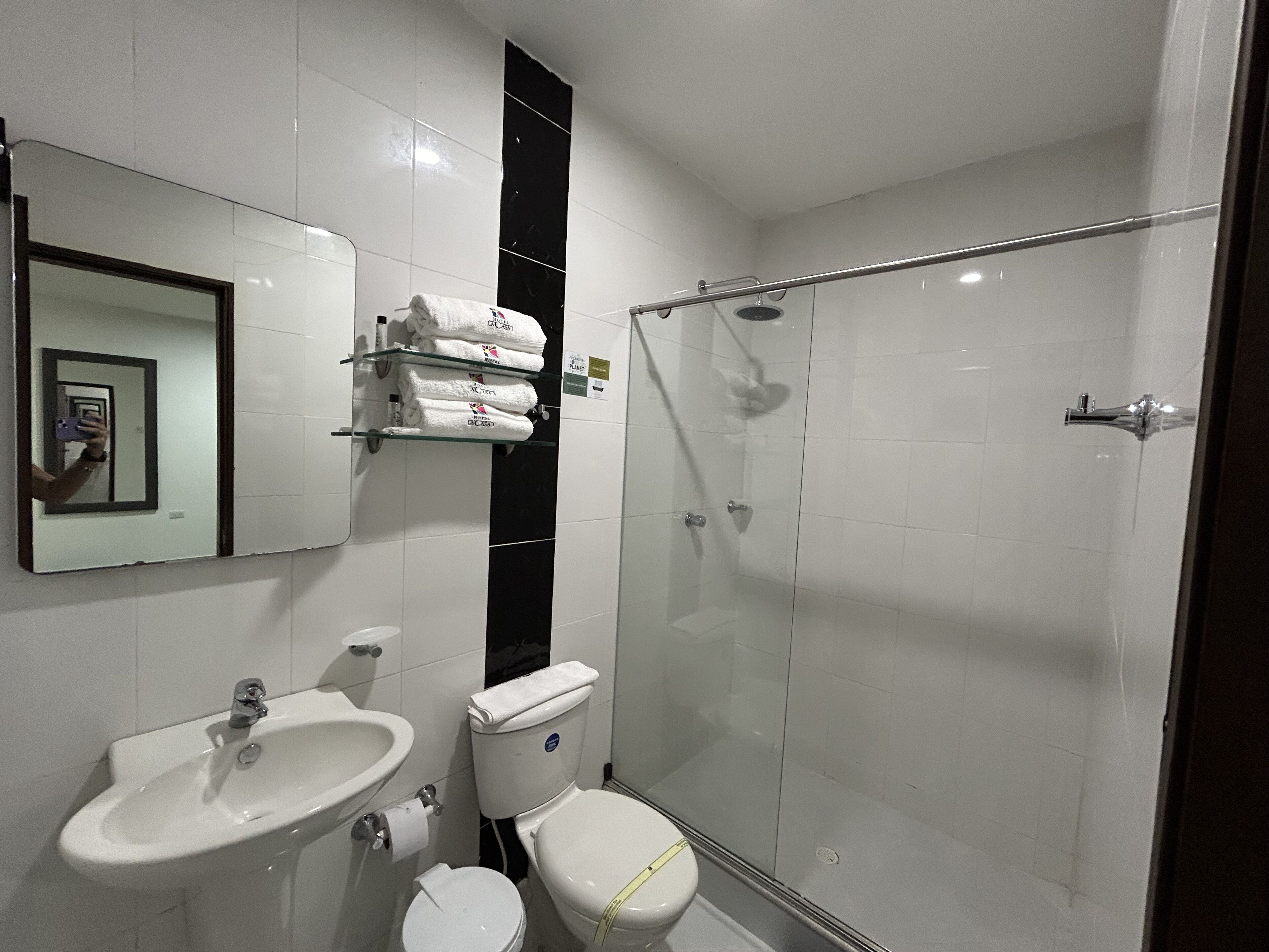 Un baño con lavamanos, inodoro y ducha con mampara de vidrio.