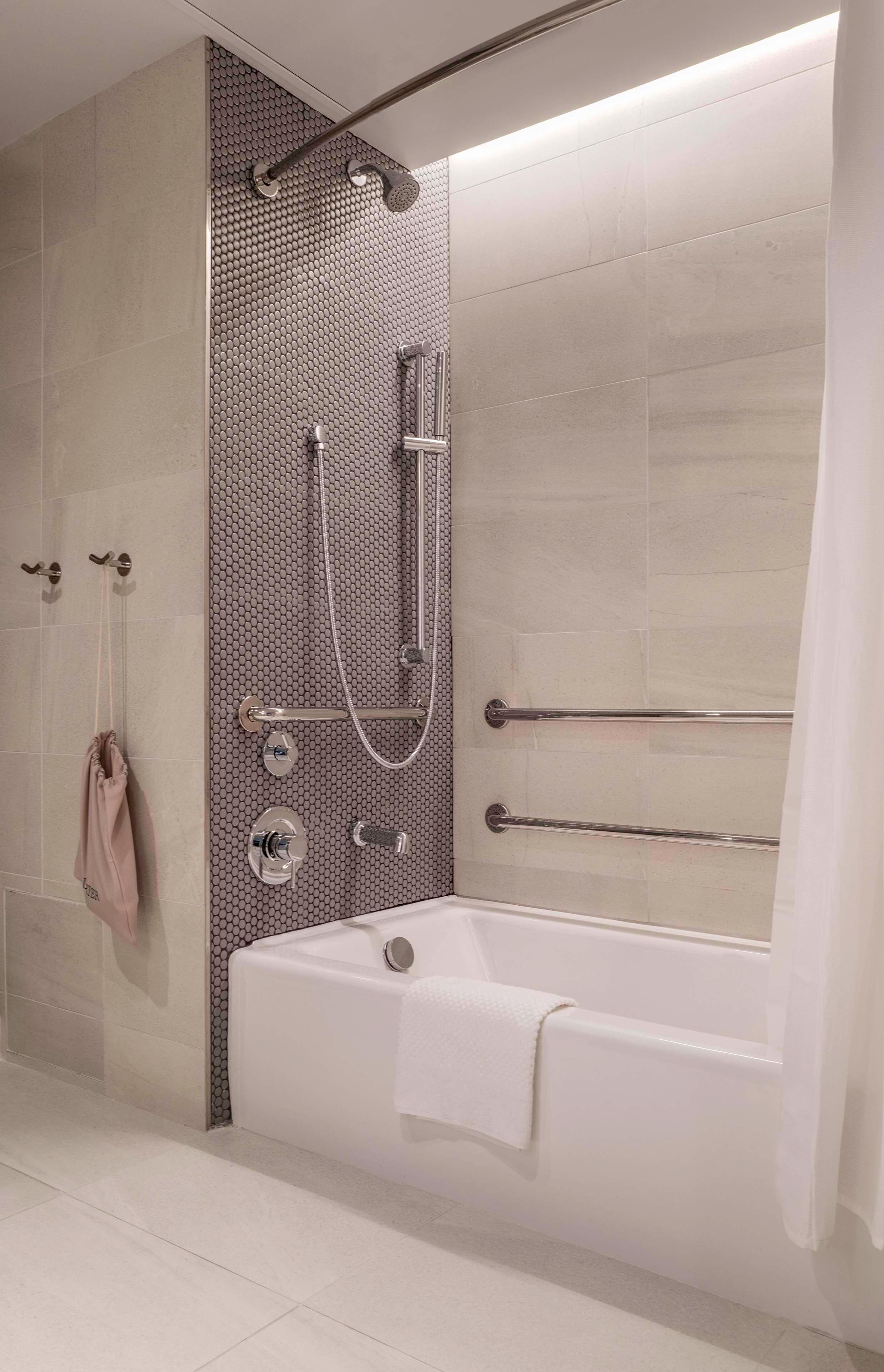 Un baño moderno con ducha, bañera y barras de apoyo.