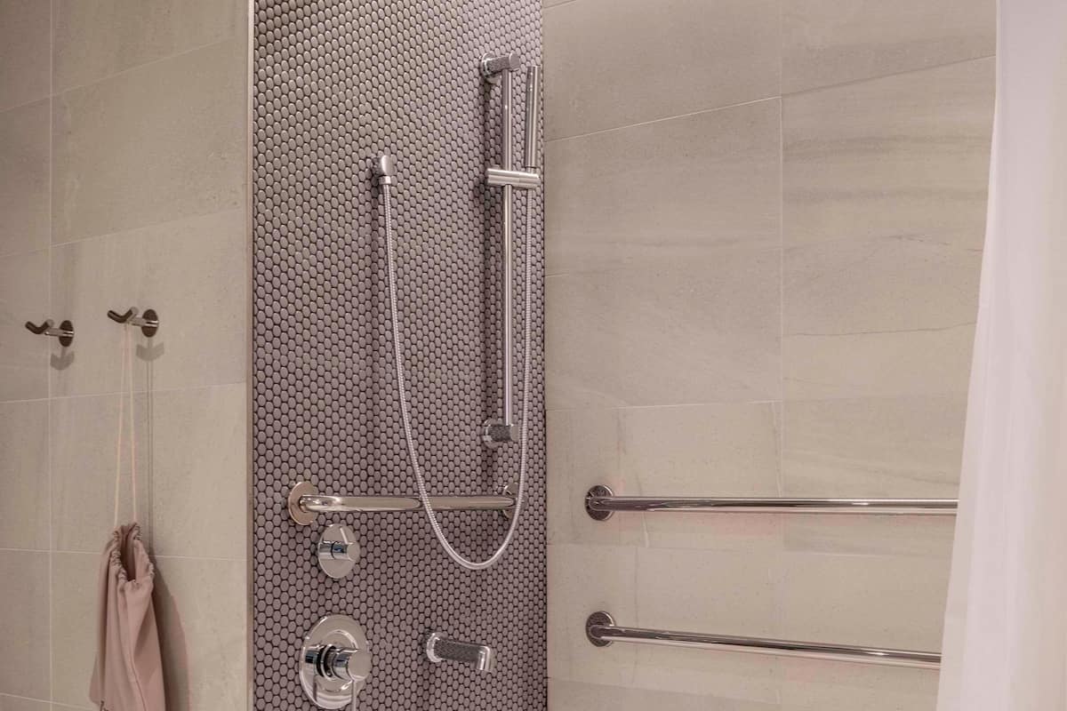 Un baño moderno con ducha, bañera y barras de apoyo.
