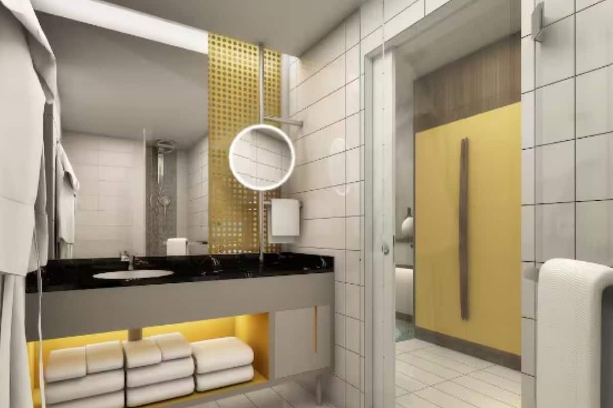Un baño moderno con encimera negra, lavabo blanco, espejo y toallero.