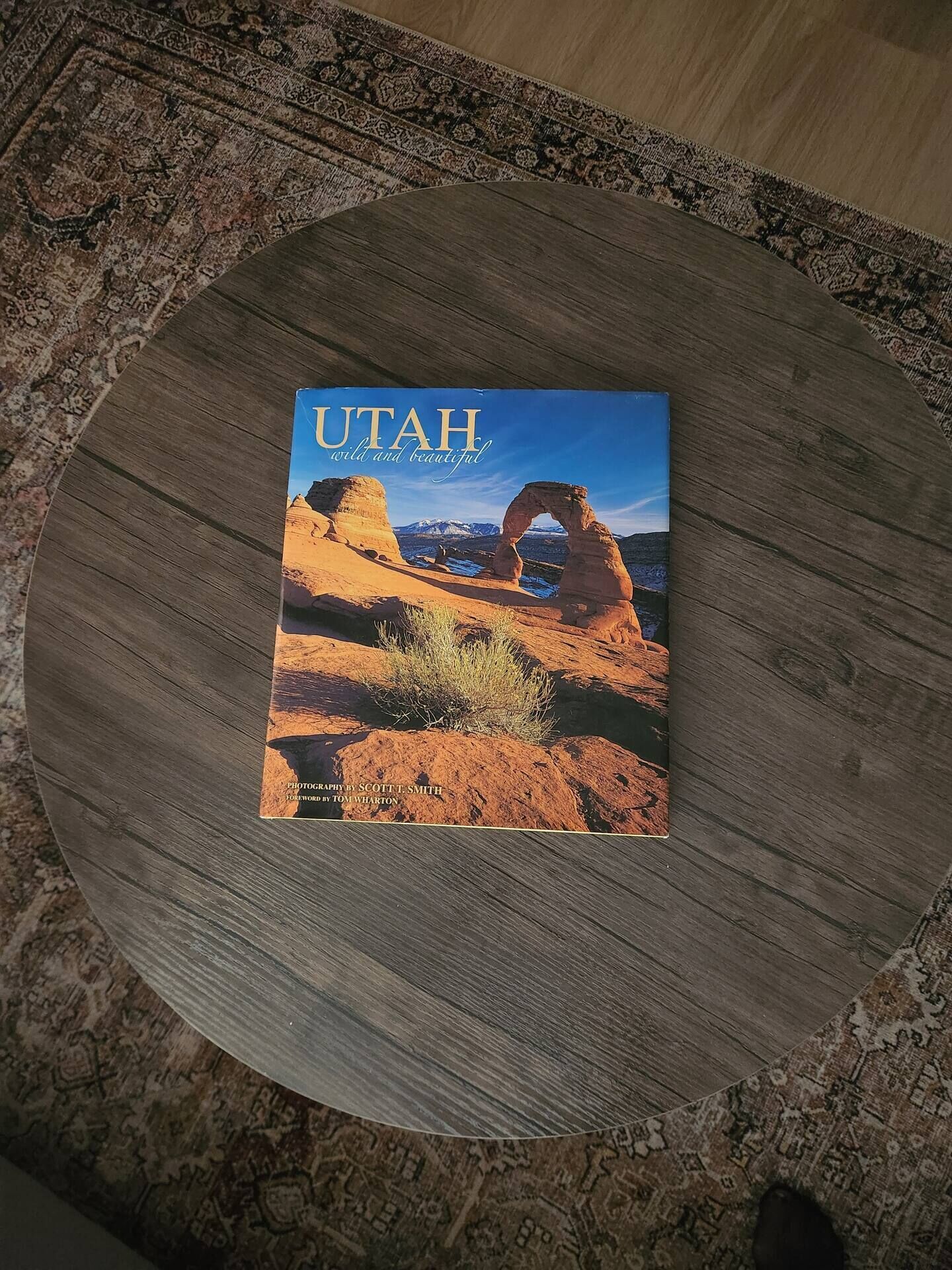 A book titled "UTAH wild and beautiful" on a round wooden table.