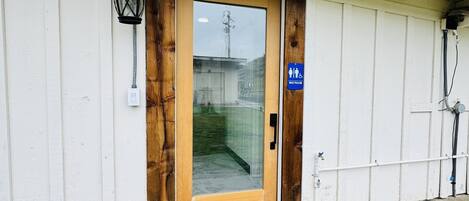 Un edificio con puerta de madera, un letrero azul para baño y un farol negro.