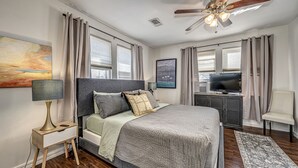 A bedroom with a bed, a TV, a desk, and a ceiling fan. - Artist Cottage - Walk to Great Shops and Restaurants  (Oklahoma City)