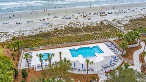 Een resort met een zwembad, toegang tot het strand en palmbomen.