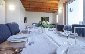 A dining table set with plates, glasses, and cutlery, with a vase of flowers in the center.