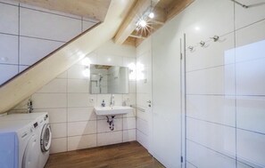 A modern bathroom with a built-in washing machine, a sink, and a shower.