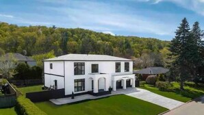 A two-story white house with a front porch and a well-maintained lawn. - Modern, Bright, Spacious 2 Bedroom Guest Suite - Entire Separate Basement  (Grimsby)