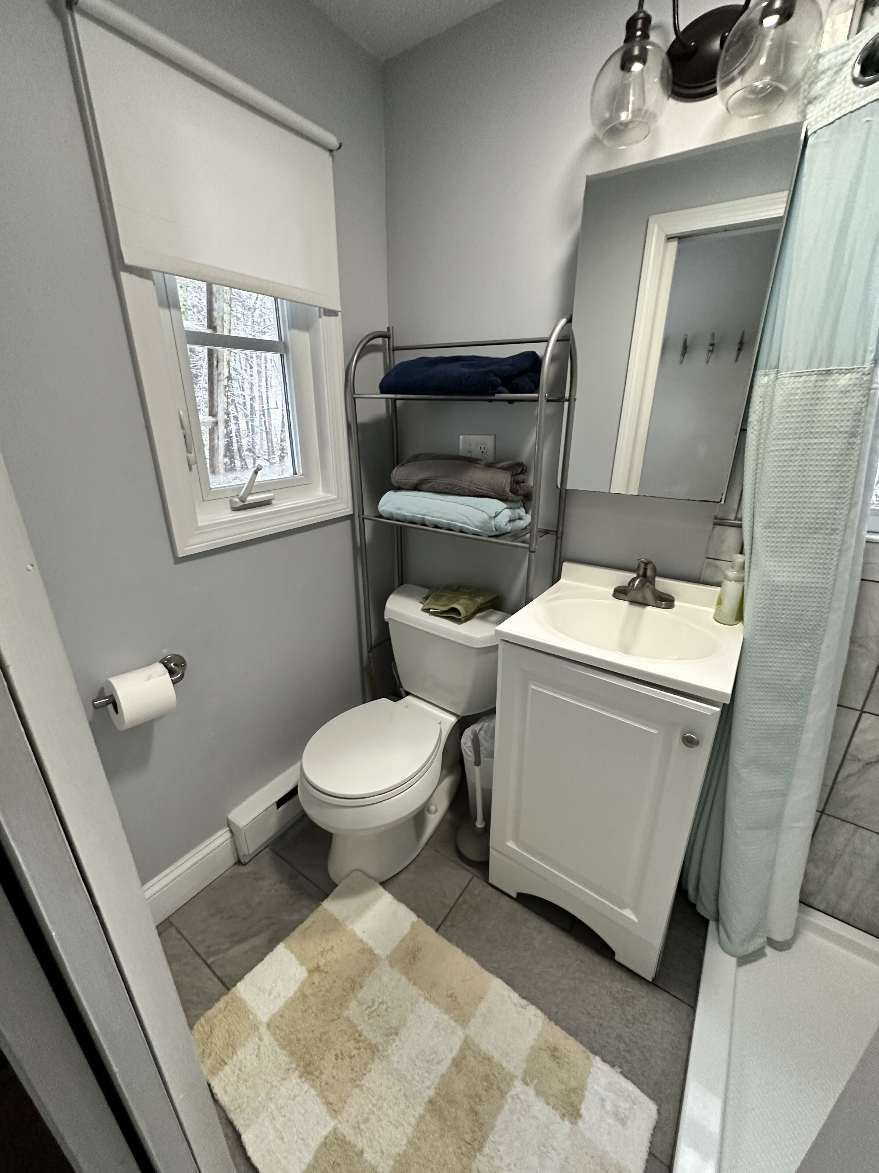 A compact bathroom with a toilet, sink, and a window.