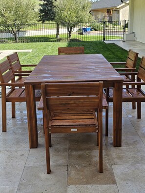 An outdoor wooden table with benches, surrounded by a paved patio area. - West Side 3BR/3BA - En suite layout, Pool&Hot Tub, nestled in oak covered hills! (Atascadero)
