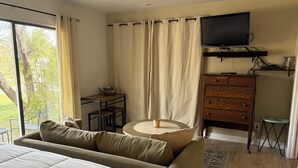Een slaapkamer met een groot bed, een bank, een televisie, een dressoir en een tafeltje.