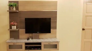 Un televisor de pantalla plana montado en una pared de madera con una encimera de mármol debajo.