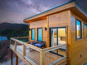 Een houten chalet met balkon, een bed en een raam met uitzicht op een landschap.