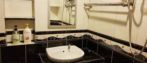 A bathroom with a white sink, black and white tiled walls, and a shower area.