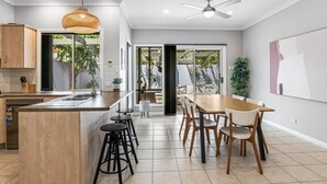 A modern kitchen with a central island, bar stools, and a dining area with a table and chairs.