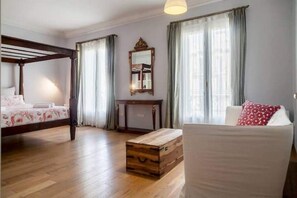 Classic hotel room with a four-poster bed, sofa, and wooden chest of drawers.