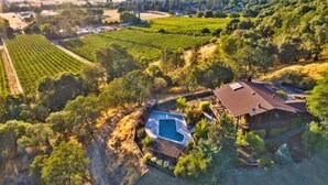 An aerial view of a property with a swimming pool, vineyard, and a large house with a sloped roof. - Verona: Awesome Views, Pool, Vineyard, Hot Tub! (Ukiah)
