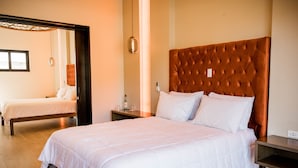A hotel room with two beds, a wooden headboard, a bedside table, and a mirror. - Limbo Hotel Boutique (Valle de Guadalupe)