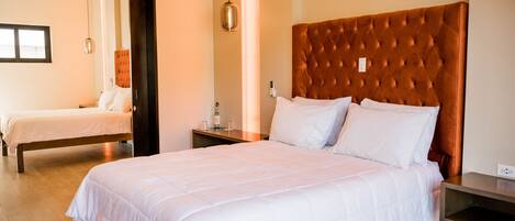 A hotel room with two beds, a wooden headboard, a bedside table, and a mirror.