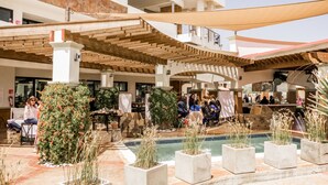 An outdoor pool area with a wooden pergola, seating, and potted plants. - Limbo Hotel Boutique (Valle de Guadalupe)