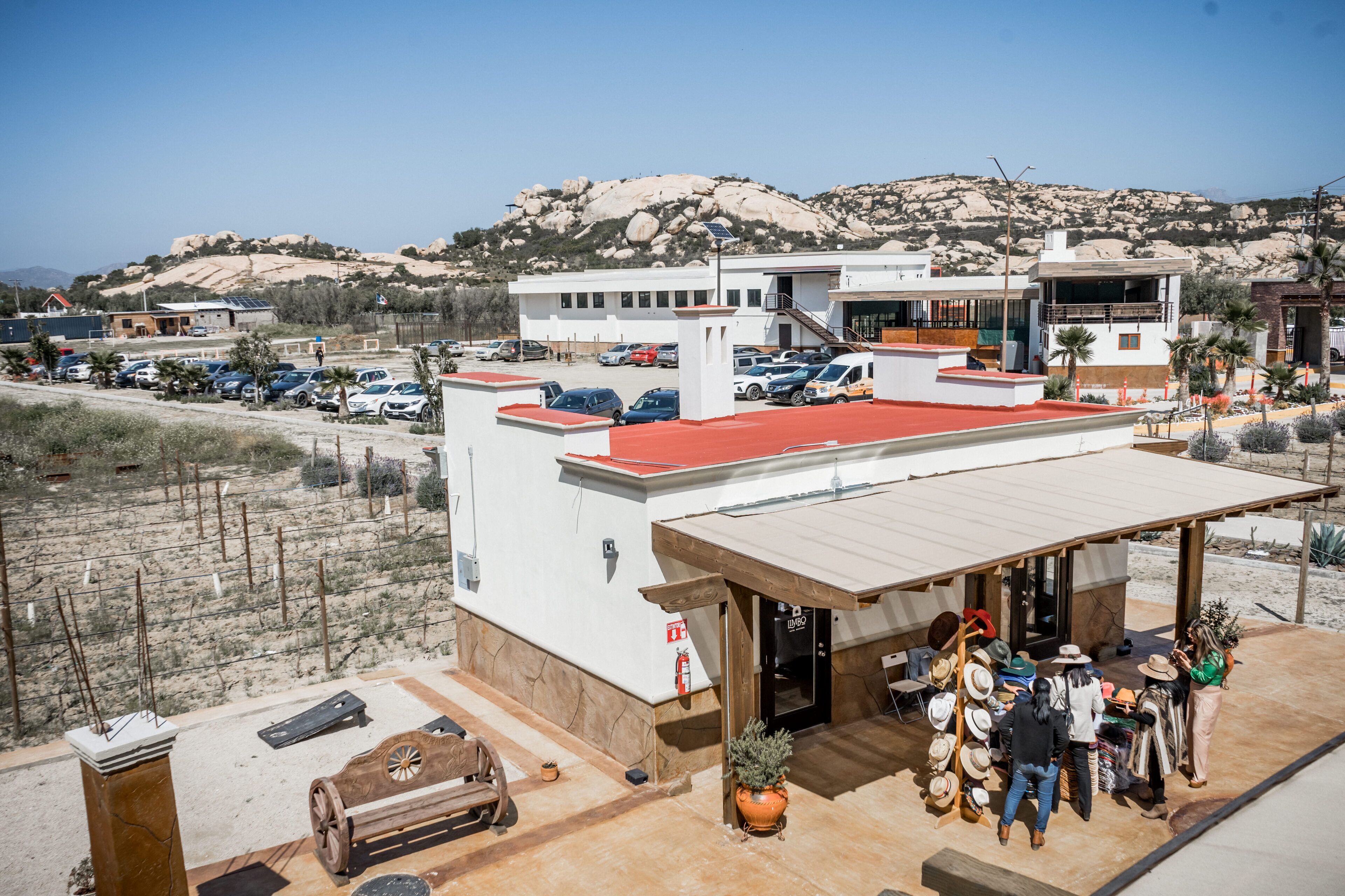 A hotel with a red roof, a covered outdoor area with a wooden bench, and a mountain backdrop.