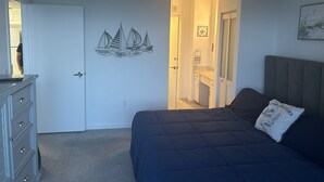 Une chambre à coucher avec un lit, une commode et un mur décoré d’une fresque représentant un voilier.