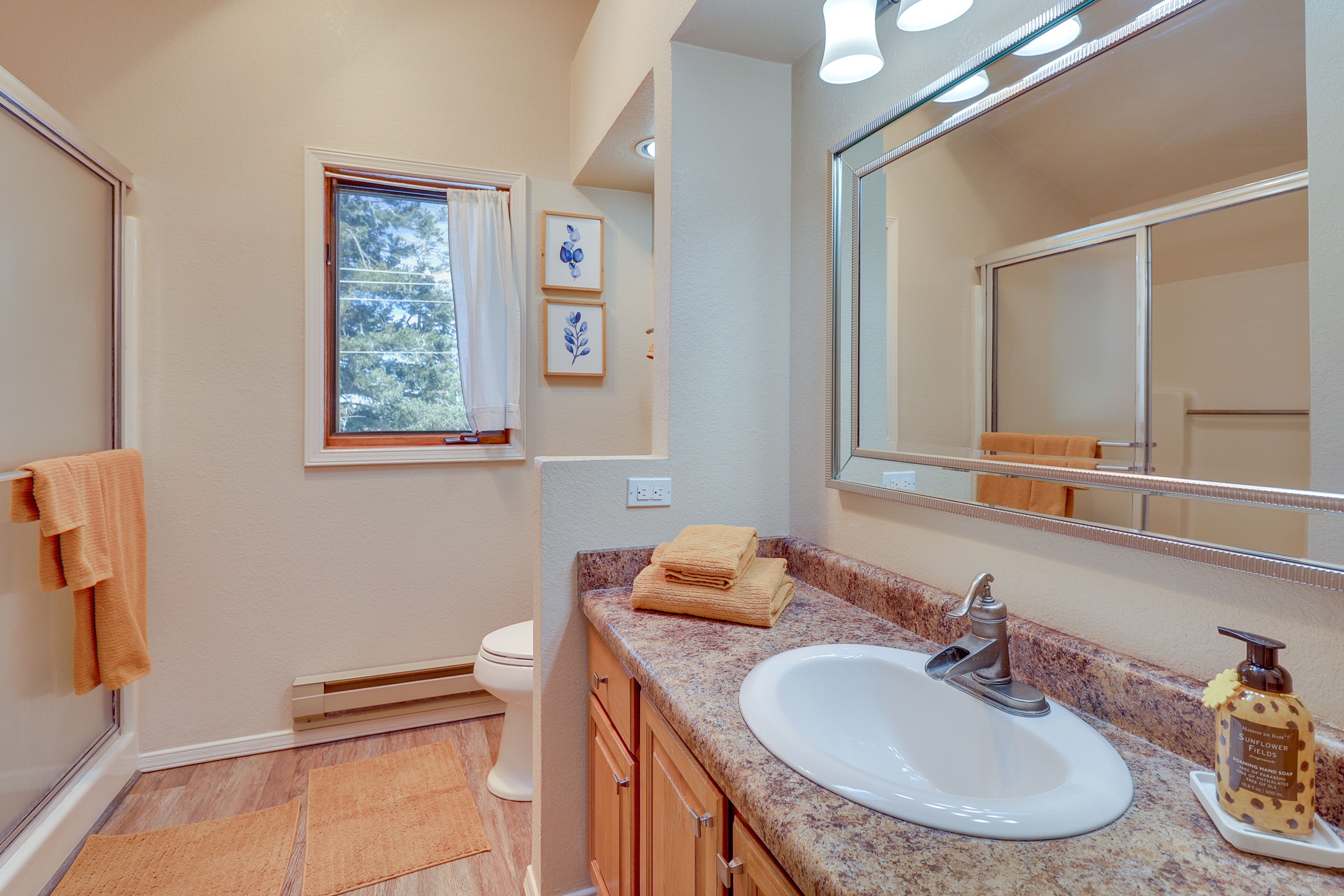 A bathroom with a white sink, a large mirror, and a window with a view of trees.