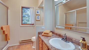 A bathroom with a white sink, a large mirror, and a window with a view of trees.