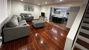 A modern living room with a grey sofa, ottoman, and a flat-screen TV. - Spacious 3 Bedroom Home in Ewing, NJ – Modern Comfort in a Prime Location (Trenton)