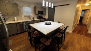 A modern kitchen with a central island, stainless steel appliances, and a dining area with wooden chairs. - Spacious 3 Bedroom Home in Ewing, NJ – Modern Comfort in a Prime Location (Trenton)