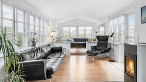 Ein geräumiges Wohnzimmer mit einer schwarzen Ledersofa, einem schwarzen Sessel, einem runden Couchtisch und einem Kamin.