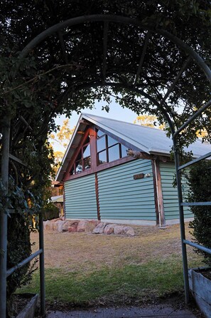 A small building with a sloped roof and a window, surrounded by a metal archway and trees. - The Family Chalet (Eukey)