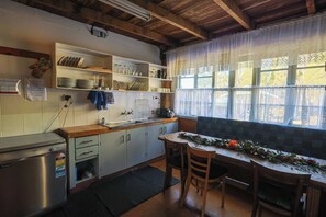 A kitchen with wooden cabinets, a refrigerator, a sink, and a window with lace curtains. - The Family Chalet (Eukey)