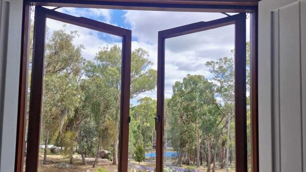 A room with a large window revealing a garden view.