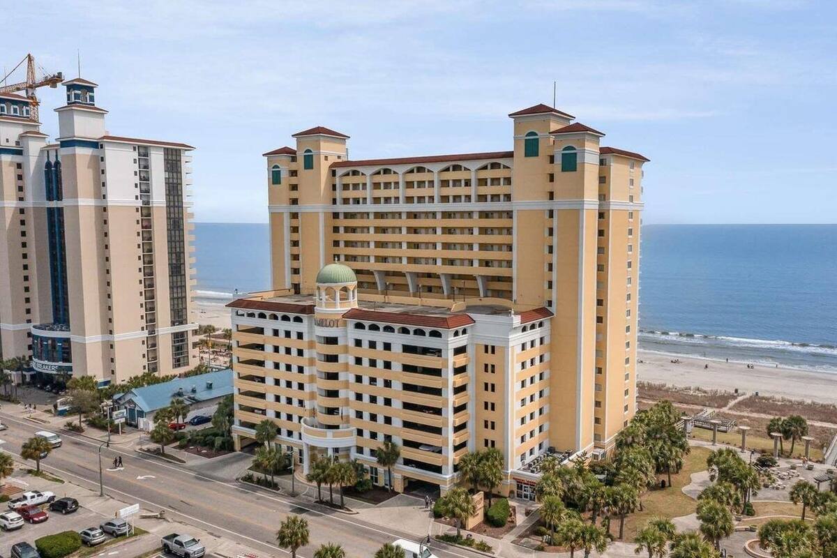 Un hôtel à plusieurs étages, doté d’un dôme central et offrant une vue sur la plage.