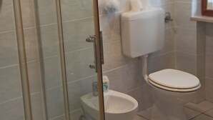Un bagno con doccia vetrata, un water e un lavandino.
