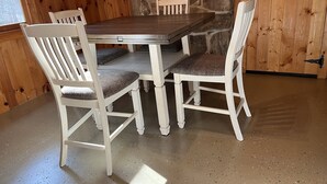 A wooden dining table with four chairs, a stone wall, and a wooden door. - Cabin joins Lost River State Park! Convenient to most popular hiking trail.  (Mathias)