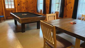 A wooden room with a pool table, a dining table, and chairs. - Cabin joins Lost River State Park! Convenient to most popular hiking trail.  (Mathias)
