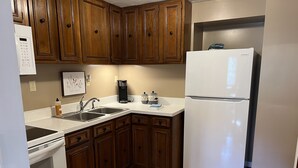 A kitchen with wooden cabinets, a white refrigerator, a coffee maker, and a stove. - Cabin joins Lost River State Park! Convenient to most popular hiking trail.  (Mathias)