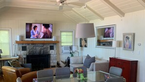 Amplia sala de estar con chimenea, televisión y comedor con sillas y mesa.