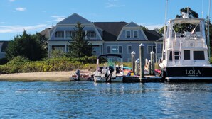 A waterfront property with a large house, docked boats, and a marina.