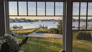 A view from a window overlooking a marina with boats, a sandy beach, and greenery.