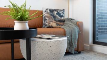 Un salon moderne avec un canapé, une table basse et une fougère en pot.