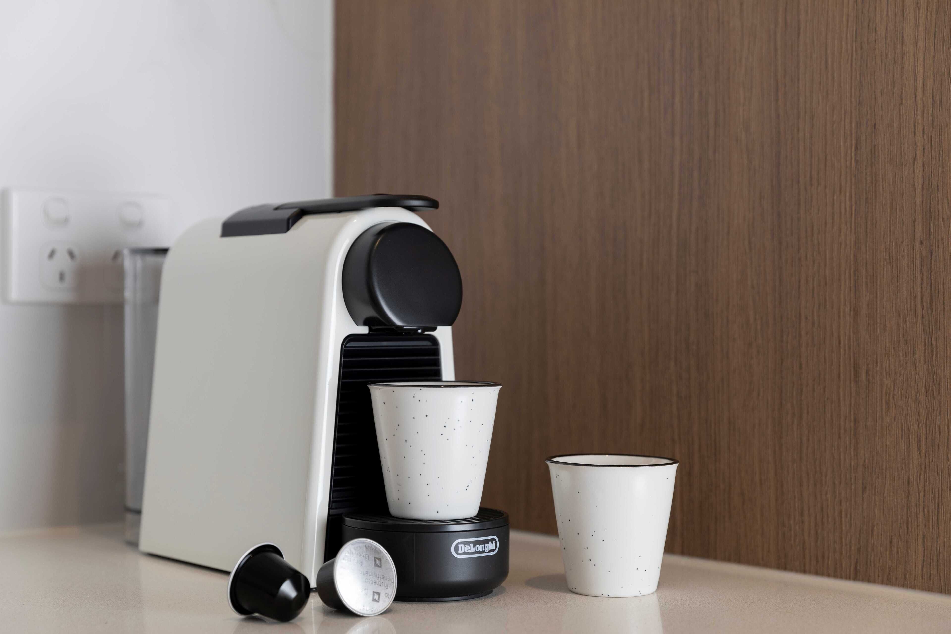 A coffee maker with two cups on a countertop.