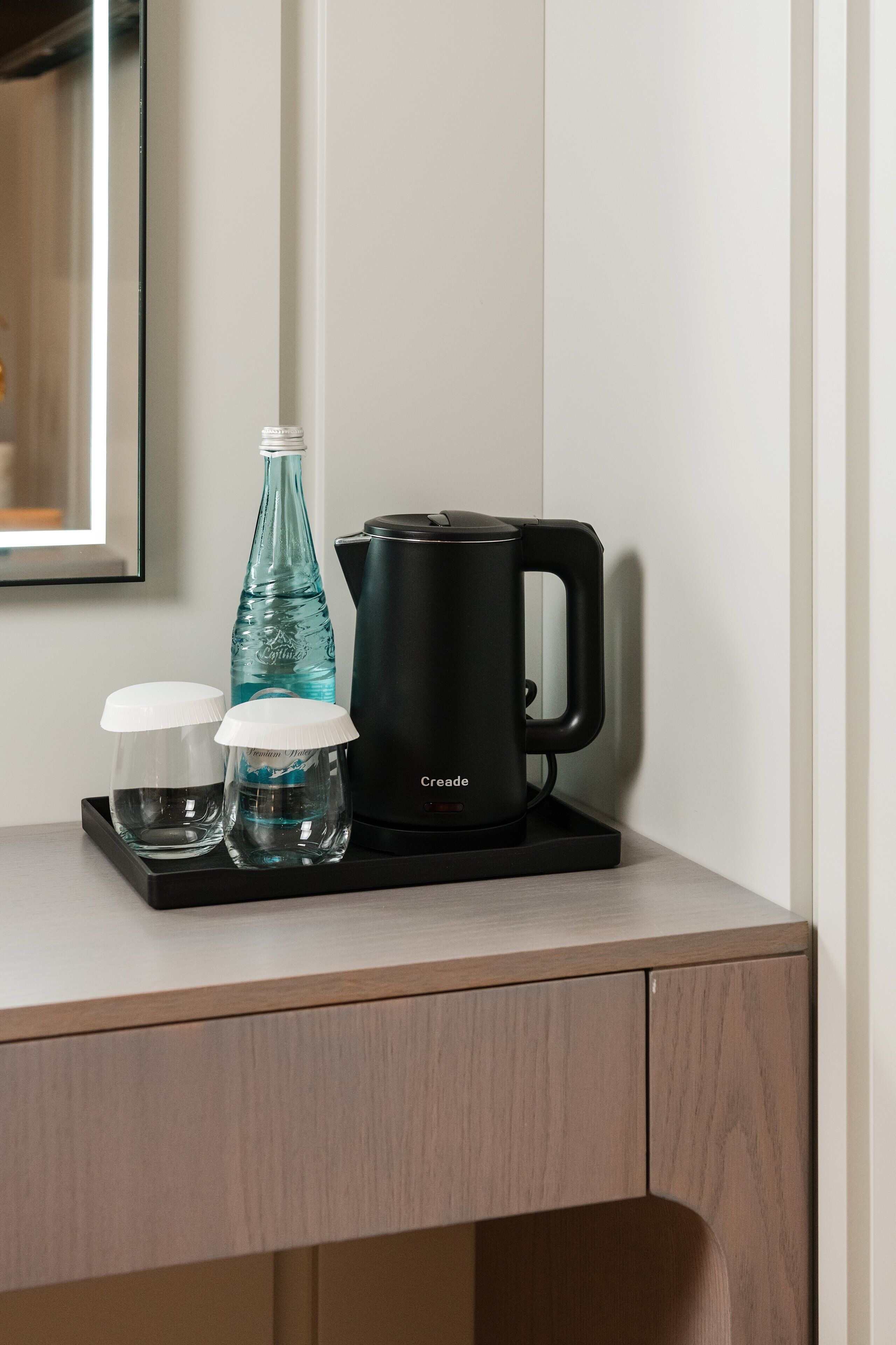 Une machine à café, une bouteille et deux verres sur un plateau.