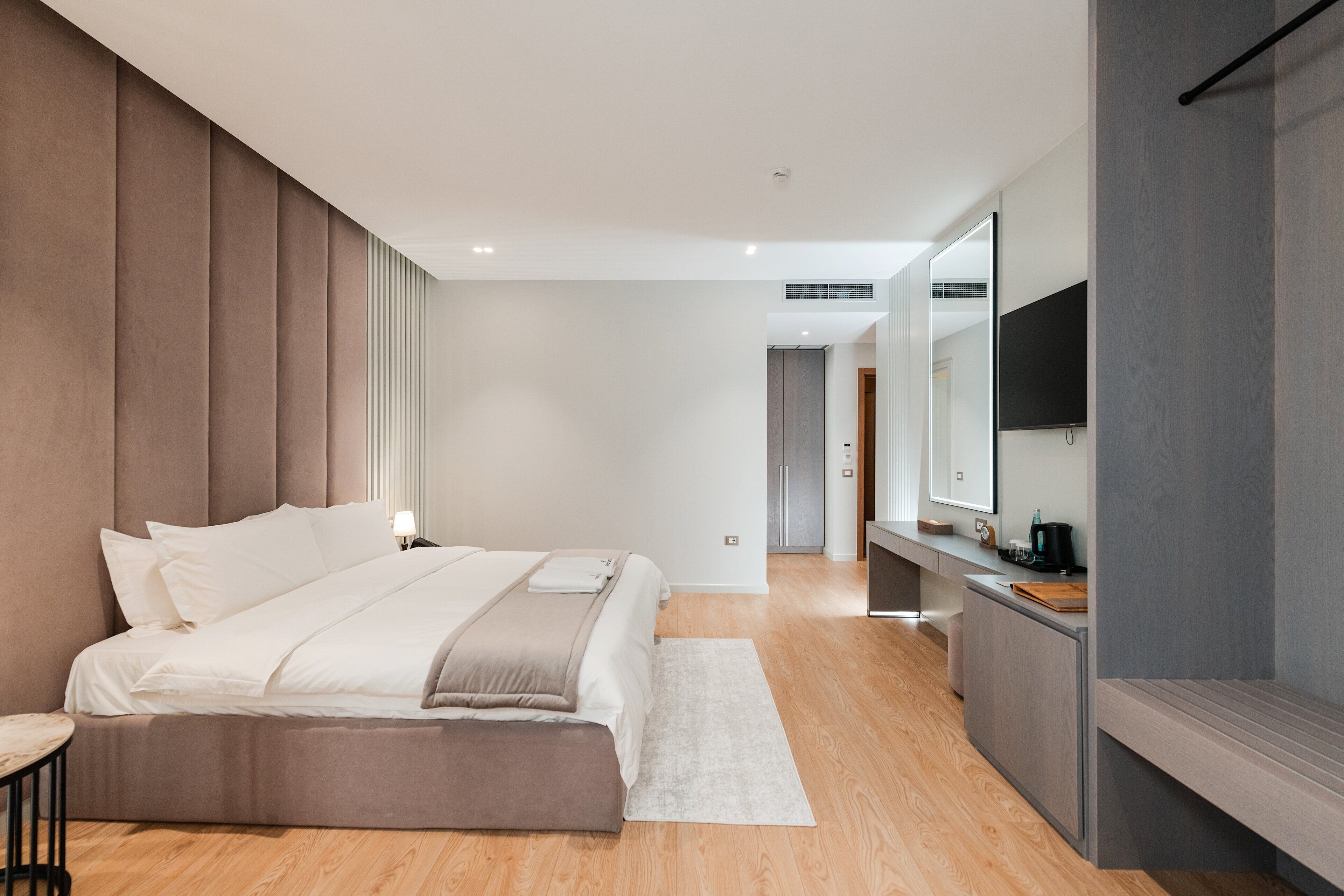 A modern bedroom with a large bed, bedside table, and a TV mounted on the wall.